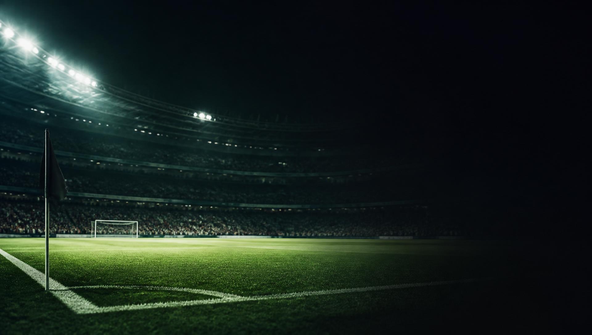 Estádio de futebol iluminado à noite com relva verde brilhante